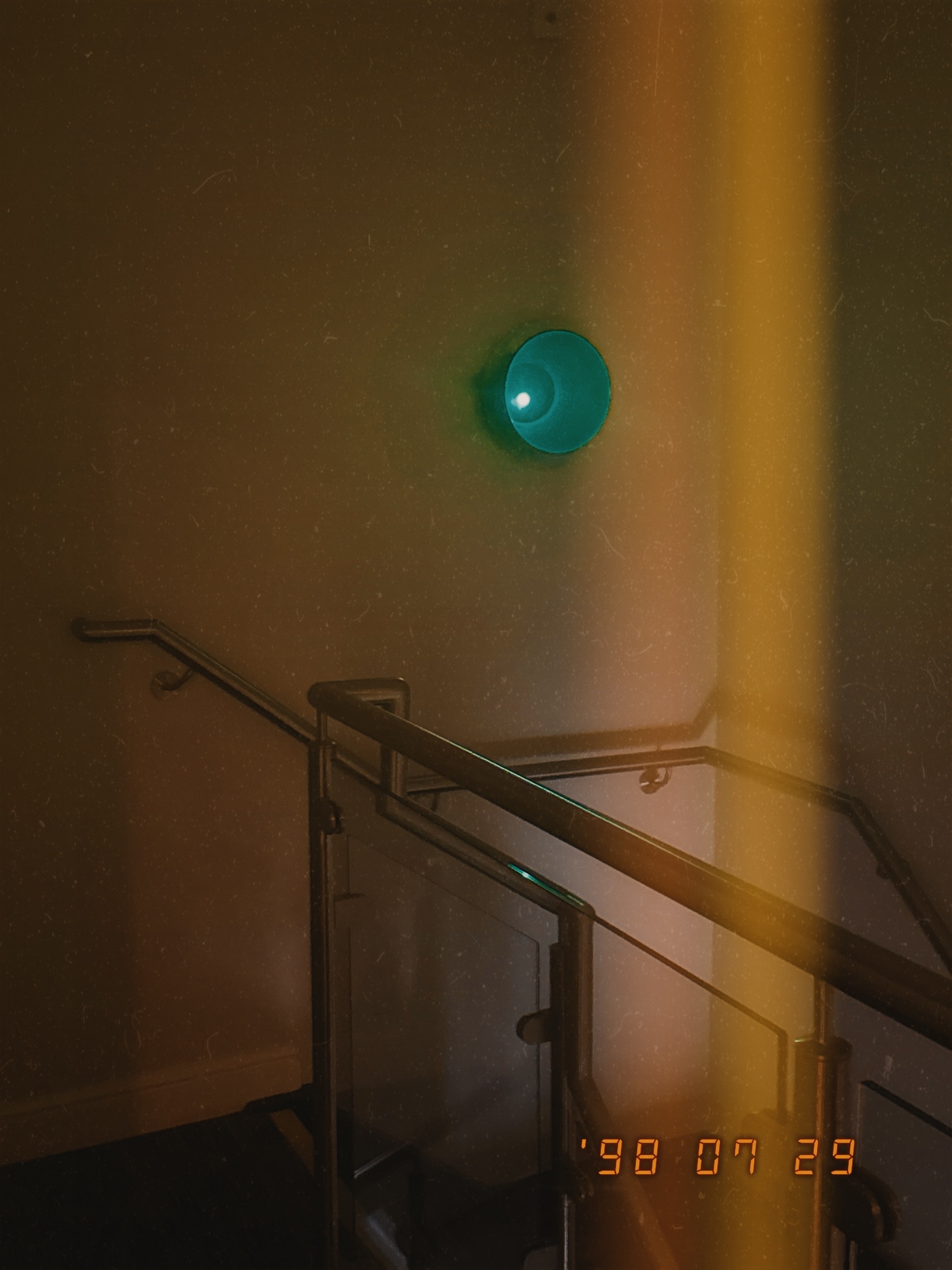 Grainy stairwell photograph with an orange light leak and date stamp